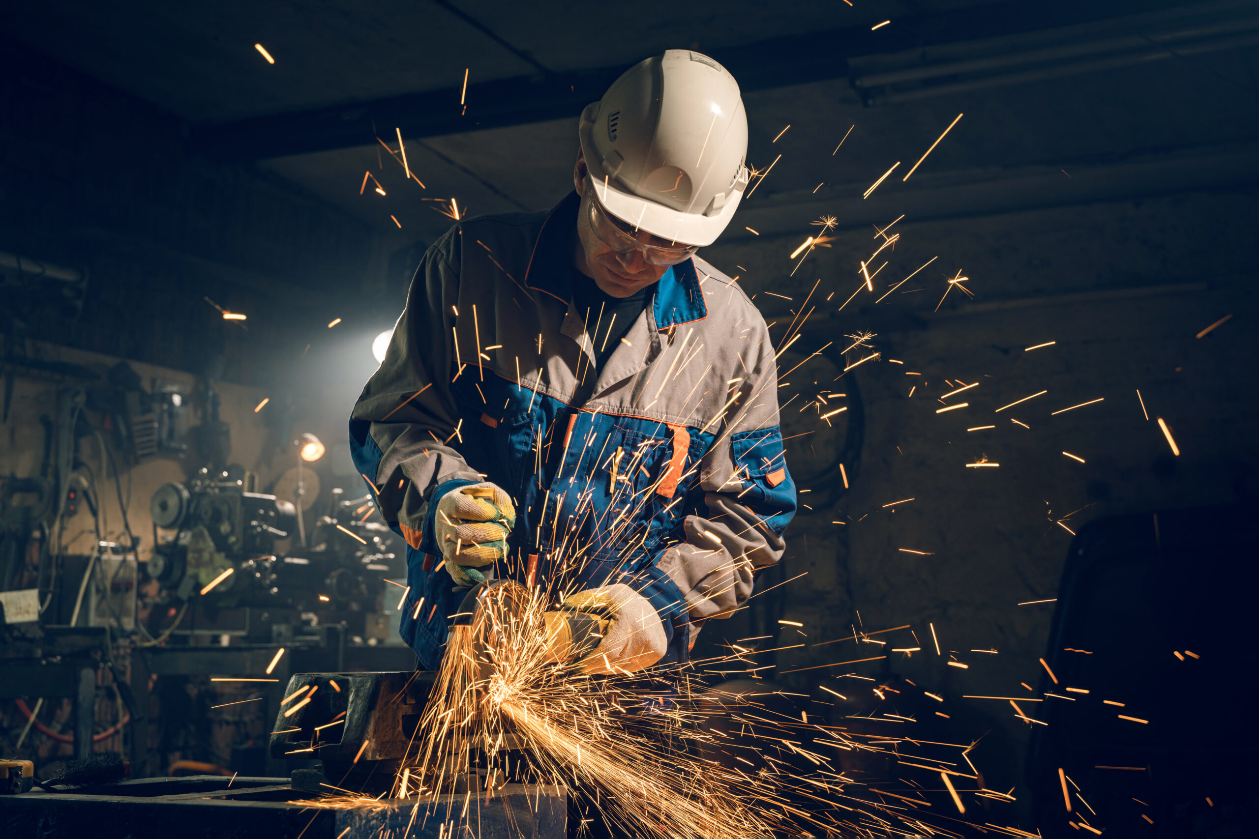 Metalworker processing with an angle grinder